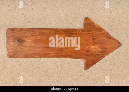 Pfeil aus einem alten Holzbrett auf dem Sand. Stockfoto