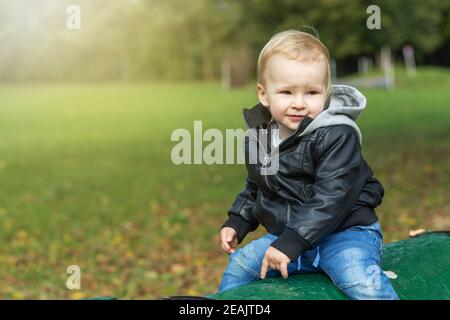 Kleiner Junge in einer Lederjacke posiert draußen Stockfoto