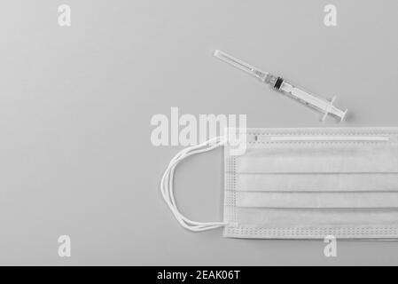 Medizinische Maske chirurgische Schutzvirus, Grippe, Krankheit, Pillen und Spritze. Isoliert auf einem rosa Hintergrund. Stockfoto