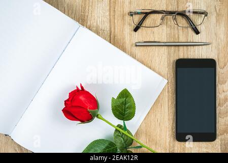 Rote Rosen auf leerem Notizbuch Tagebuch mit Smartphone Valentine Konzept Stockfoto