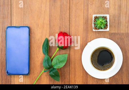 Weiße Tasse Kaffee und rote Rose mit Handy valentine Konzept Stockfoto