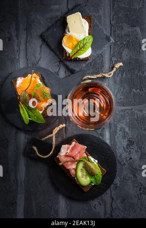 Variation von gesunden offenen Sandwiches auf Pumpernickel Brot mit Gemüse, Lachs, Schinken, Kräutern und Weichkäse Stockfoto