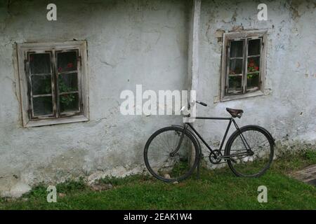 Ein altes Fahrrad an eine Wand gelehnt Stockfoto