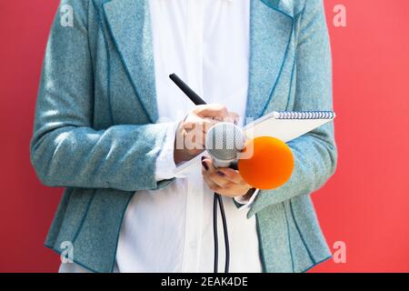 Journalistin bei Pressekonferenz, Schreiben von Notizen, mit Mikrofon Stockfoto