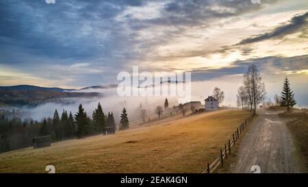 Alpendorf. Ländliche Herbstlandschaft. Kalter Novembermorgen. Morgennebel im Bergtal Stockfoto