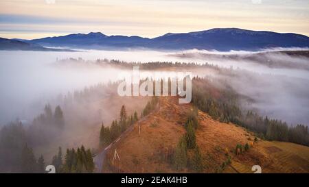 Kalter Novembermorgen. Morgennebel im Bergtal. Wald bedeckt von niedrigen Wolken. Nebliger Herbstwald Stockfoto