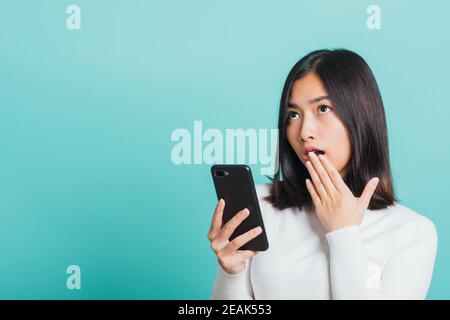 Frau überrascht schockiert mit Handy schließen Mund mit Handfläche Stockfoto