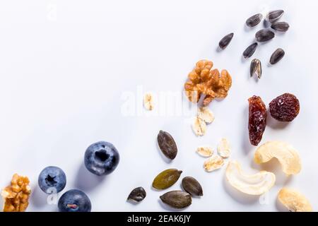 Samen von Sonnenblumen, Nüssen, Früchten und getrockneten Früchten auf weißem Hintergrund mit Kopierraum. Stockfoto