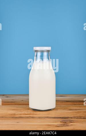 Schließen Sie eine Glasflasche Milch über Blau Stockfoto