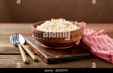 Sauerkraut, fermentierter Kohl mit Karotten in Schüssel auf Holzgrund. Superfoods zur Unterstützung des Immunsystems. Stockfoto