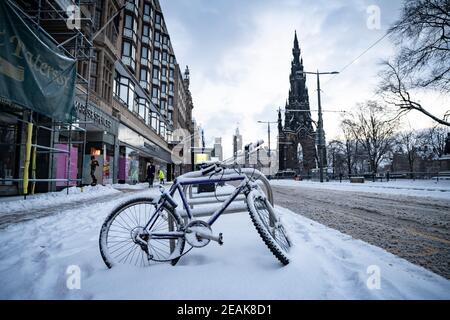 Edinburgh, Schottland, Großbritannien. Februar 2021, 10. Große Frost in Großbritannien mit schweren Nacht-und Morgenschnee in der Stadt weiter. PIC; schneebedecktes Fahrrad auf der Princes Street. Iain Masterton/Alamy Live Nachrichten Stockfoto