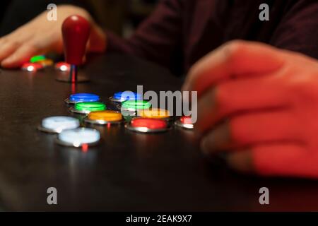 Nahaufnahme Ansicht von zwei Menschen Hände spielen Arcade vintage Video Games.Gamepad mit Joystick und viele bunte Tasten.Gaming Konzept Lifestyle Mit cre Stockfoto