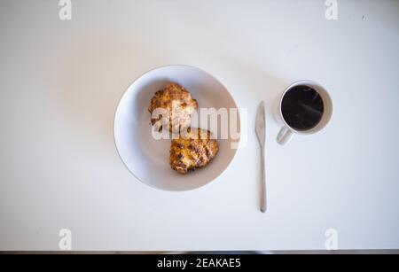 Zwei Kekse neben einer Tasse Kaffee auf einem Weißer Tisch Stockfoto