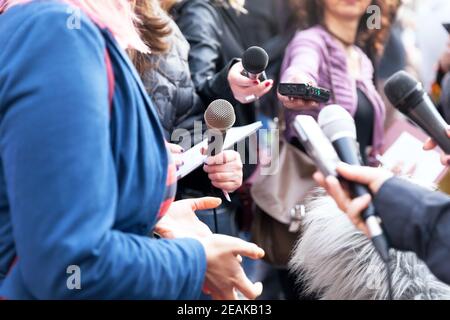 Öffentliche Person im Gespräch mit den Medien, Journalisten halten Mikrofone bei der Pressekonferenz Stockfoto