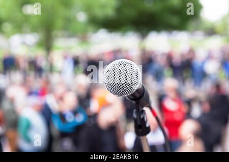 Mikrofon im Fokus, verschwommene Menschen bei Straßenprotesten im Hintergrund Stockfoto