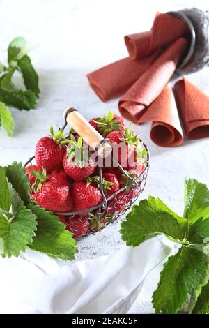 Erdbeeren in einem Korbkorb aus Metall und Erdbeermarmelibe auf einem schlechten Hintergrund. Blick von oben. Gesunde Ernährung Konzept. Vertikales Foto. Stockfoto