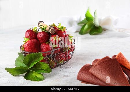 Erdbeeren in einem Korbkorb aus Metall und Erdbeermarmelibe auf einem schlechten Hintergrund. Blick von oben. Gesunde Ernährung Konzept. Stockfoto