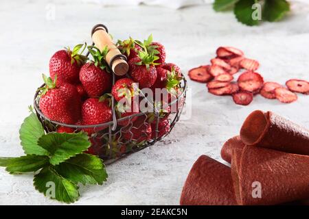 Erdbeeren in einem Korbkorb aus Metall und Erdbeermarmelibe auf einem schlechten Hintergrund. Blick von oben. Gesunde Ernährung Konzept. Getrocknete Beerenscheiben. Stockfoto