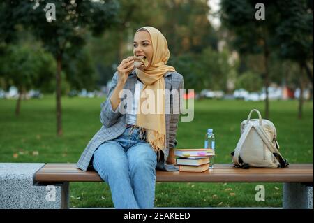 Arabische Studentin sitzt auf der Bank im Park Stockfoto