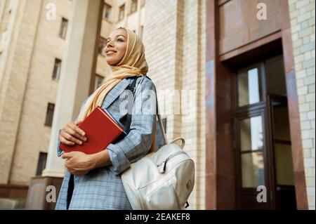 Arabisches Mädchen mit Büchern posiert am Eingang der Universität Stockfoto