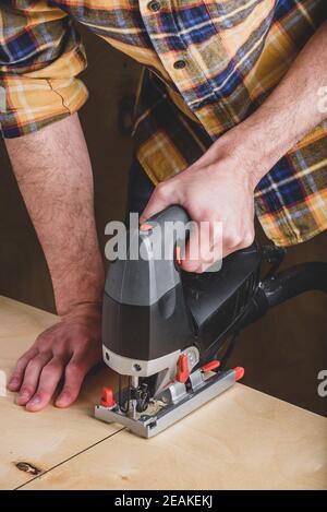 Mann mit elektrischer Spannsäge Holz schneiden Stockfoto