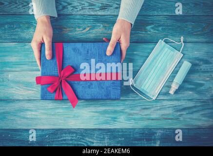 Hände der Frau halten Geschenk-Box. Konzeptuelles Symbol des Weihnachtsfestes in Pandemia von COVID19. Stockfoto