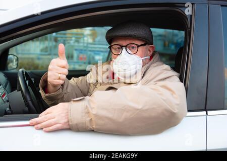 Männlicher Senioer mit Gesichtsmaske zeigt die neue Normalität Stockfoto