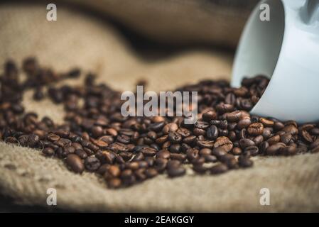 Kaffeebohnen verschüttet aus Tasse Stockfoto