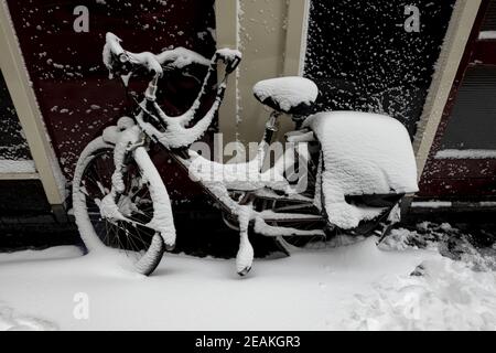 ZUTPHEN, NIEDERLANDE - 08. Feb 2021: Außenfassade mit einem dicken Pack Schnee auf einem einzigen niederländischen Stadtfahrrad, das mit einer Fahrradtasche an der Außenseite verriegelt ist Stockfoto