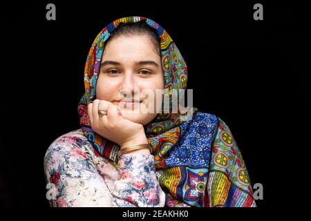 Portrait eines Teenagermädchen mit bunten Kleidern in Vorderseite mit schwarzem Hintergrund Stockfoto