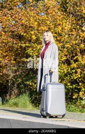 Junge blonde Mädchen posiert mit Koffer in der Eisenbahn Station Stockfoto