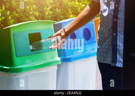 Schwarze Hand wirft eine leere Plastikwasserflasche in die Müllabfuhr wird recycelt Stockfoto