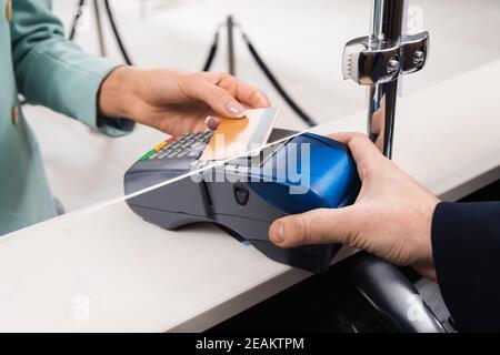 Beschnittene Ansicht des Managers, der Zahlungsterminal in der Nähe von Frau mit hält Kreditkarte im Hotel Stockfoto