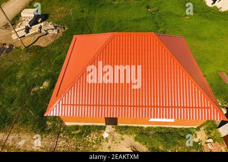 Haus mit einem orangefarbenen Dach aus Metall, Ansicht von oben. Metallische Profil gestrichen Wellpappe auf dem Dach. Stockfoto