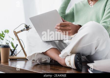 Beschnittene Ansicht des afroamerikanischen Architekten auf dem Schreibtisch mit Laptop, unscharfer Hintergrund Stockfoto