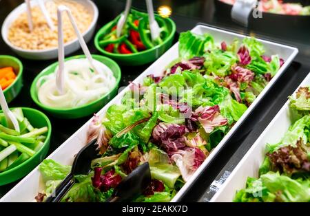 Salatbuffet im Restaurant. Frisches Salatbuffet zum Mittag- oder Abendessen. Gesunde Ernährung. Frischer grüner und violetter Salat in weißem Teller auf der Theke. Catering-Essen. Bankettservice. Vegetarisches Essen. Stockfoto