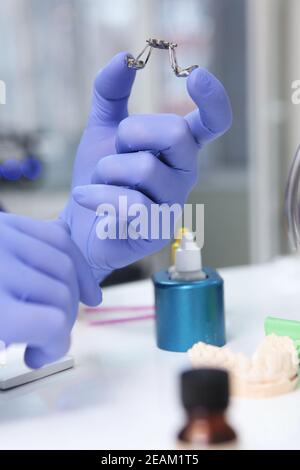 Der Arzt hält die Hosenträger. Ausrichtung des Gebisses oder Bisses. Nicht erkennbare Person. Hände in Schutzhandschuhen. Stockfoto