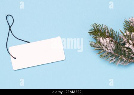 Vorlage für weihnachtsverkauf. Ein leeres Papier Preisschild und ein Tannenzweig auf blauem Hintergrund. Konzept der Winter oder Black Friday Verkauf. Leerer Raum für Design. Stockfoto