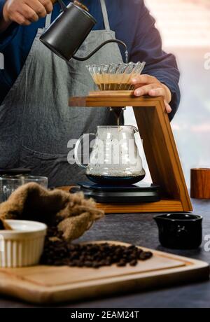 Kaffeemaschine. Barista gießt heißes Wasser über den Kaffee mit Papierfilter. Stockfoto