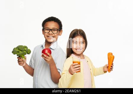 Multiethnische Gruppe von Kindern mit gesundem Gemüse, Obst und Karottensaft. Werbung für Kinder gesunde Ernährung Stockfoto