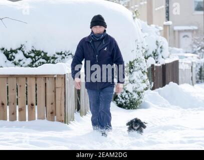 West Lothian, Schottland. Wetter: 10th Februar, 2021 Sturm Darcy: John Lamsden und sein Hund Gucci wandern durch den Schnee in Stoneyburn, West Lothian, Schottland, UK. . Quelle: Ian Rutherford/Alamy Live News. Stockfoto