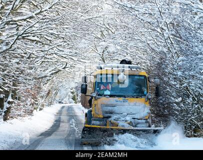 West Lothian, Schottland. Wetter: 10th Februar, 2021 Sturm Darcy: Ein Schneepflüge reinigt Schnee durch eine Allee von Bäumen in der Nähe von Stoneyburn, West Lothian, Schottland, Großbritannien. . Quelle: Ian Rutherford/Alamy Live News. Stockfoto