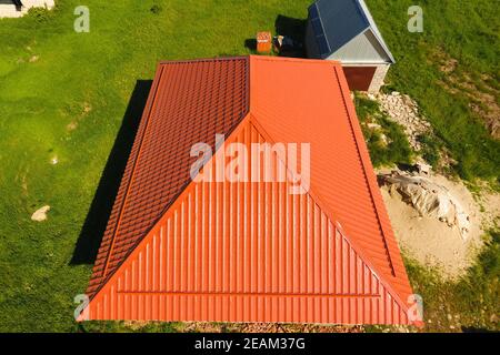 Haus mit einem orangefarbenen Dach aus Metall, Ansicht von oben. Metallische Profil gestrichen Wellpappe auf dem Dach. Stockfoto