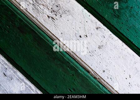 Holzhintergrund. Detail der alten hölzernen Tore, Türen mit rissiger Farbe. Grüne und weiße alte Holzbretter Stockfoto