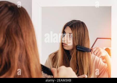 Junge Frau putzt ihr glänzendes langes braunes Haar Stockfoto