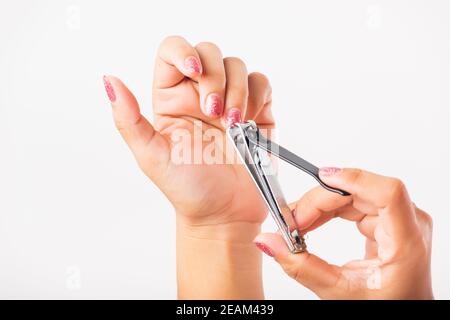 Frau schneidet Nägel am Finger mit einem Nagelschneider Stockfoto
