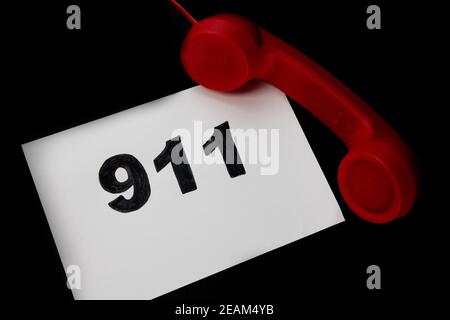 Anruf 911 und Notrufkonzept, Text 911 auf Papier und Telefon isoliert auf schwarz. Stockfoto