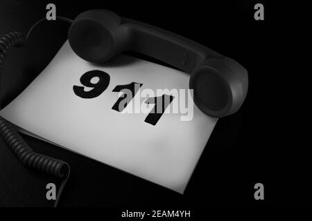 Anruf 911 und Notrufkonzept, Text 911 auf Papier und Telefon isoliert auf schwarz. Stockfoto