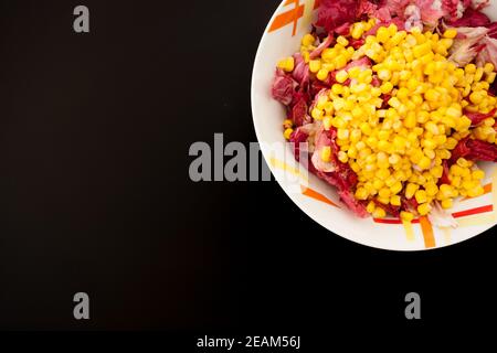 Salat mit Mais auf schwarzem Tisch, Draufsicht Stockfoto