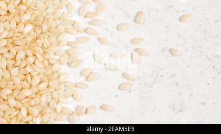 Weißer Sesam - Sesamum indicum - Samen auf weißem Stein wie Tafel, Ansicht von oben Stockfoto
